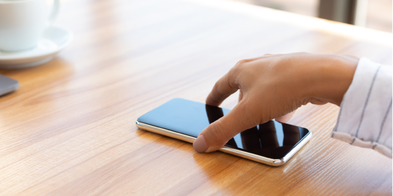 person setting a cell phone down on a desk